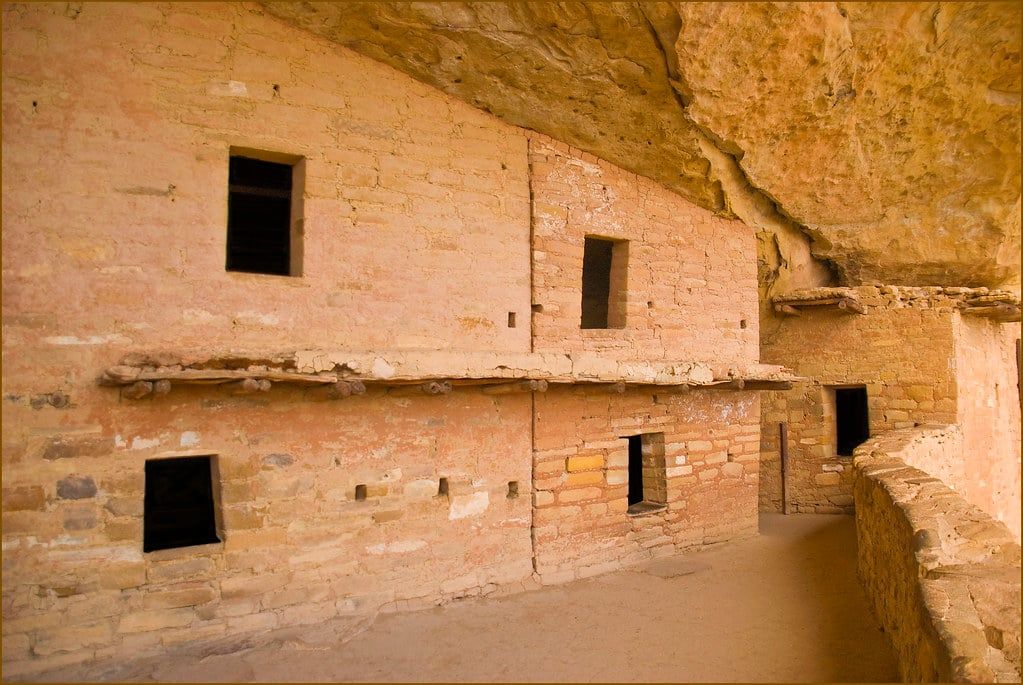 Well-preserved two-story Ancestral Puebloan stone cliff dwellings and a wooden balcony at Balcony House in Mesa Verde National Park.